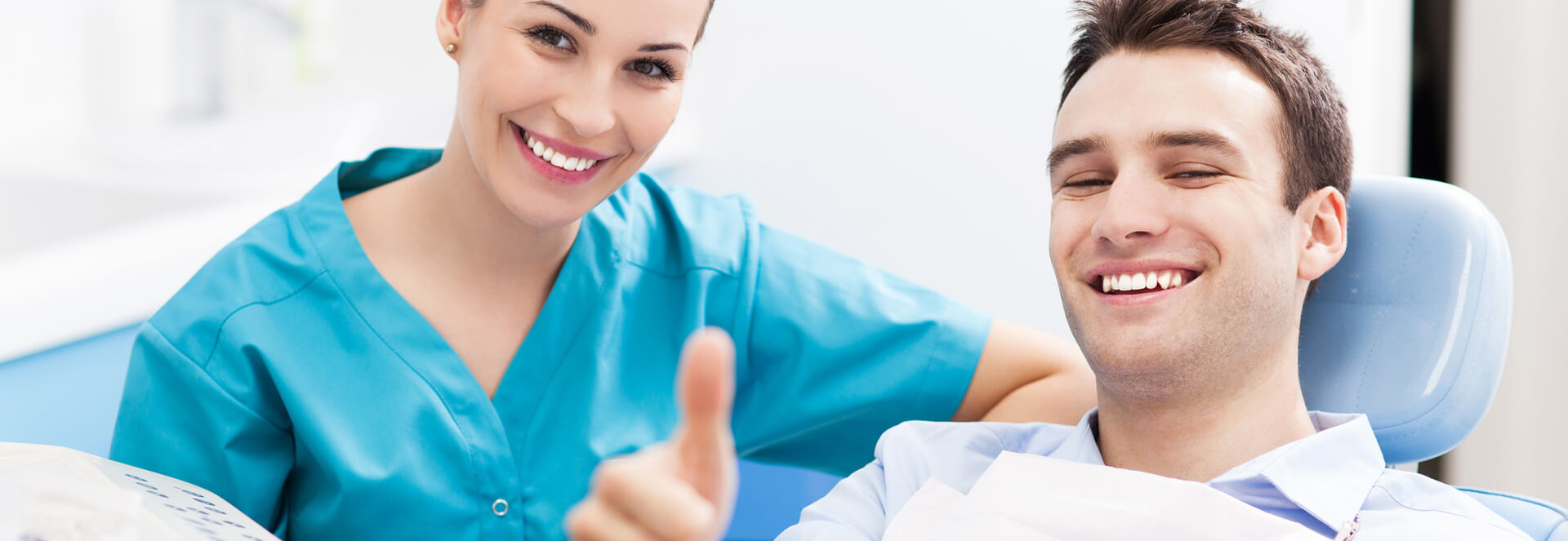 Dental assistant smiling and male patient showing thumbs up