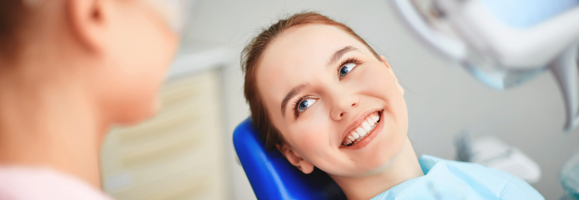 Young beautiful woman smiling seated on dental chair about to get teeth cleaned